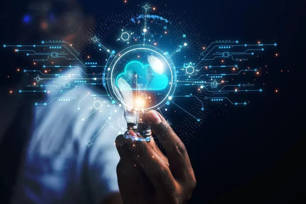 Una mano tiene una lampadina incandescente con elementi tecnologici digitali.